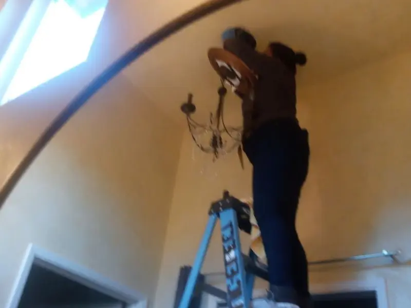 Electrician installing a chandelier in a Paragould residence